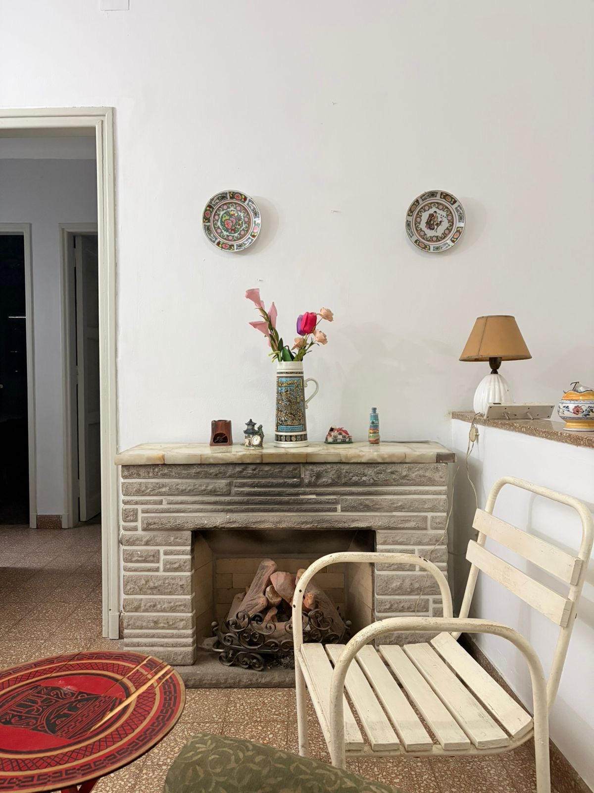 Hogar a leña, sillón y objetos en el interior de Casa Tomatis
